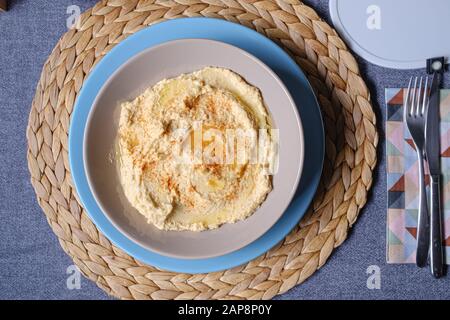 Hummus chickpea dish served on a plate on prepared fabrics dinner table Stock Photo
