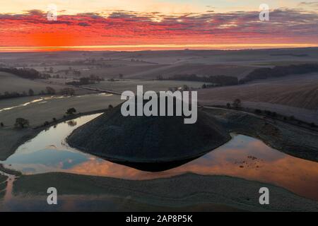 Silbury Hill, Nr Avebury, Wiltshire, UK. 20th January 2020. Drone images of a spectacular red frosty sunrise and the ancient man-made mound of Silbury Stock Photo