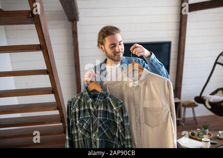 Man choosing between plaid and white shirt Stock Photo