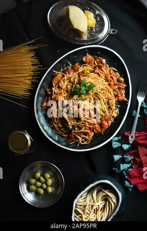 Classic Italian Spaghetti Bolognese sauce pasta in a black dish, heaped spaghetti bolognese top view with ingredients for cooking pasta, pasta dish Stock Photo