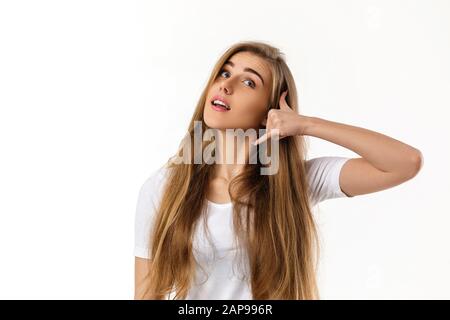 smiling young woman showing phone gesture on white background. girl makes call me back with hand Stock Photo