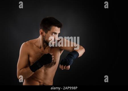 boxer man with bandage on hands training before fight and showing the different movements on black background Stock Photo