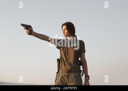 Full length portrait of pretty brunette, asian girl wearing black top and  khaki utilitarian army pants