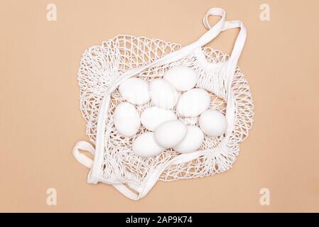 Easter table concept background with string bag, colorful Easter eggs and yellow tablecloth. Stock Photo