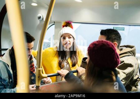 A group of friends talking while traveling in an urban bus through the city Stock Photo