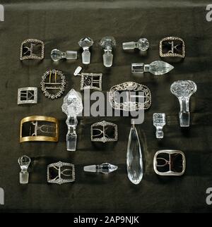 Detail of the P.M. Ward Collection at Llanerchaeron of glass and crystal bottle stoppers, a chandelier drop and silver belt buckles arranged on a dark Stock Photo