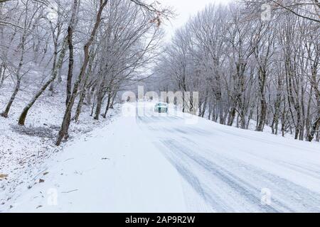 Gabala, Azerbaijan - January 20, 2020: An old Soviet car driving along a snowy road in the middle of a forest Stock Photo