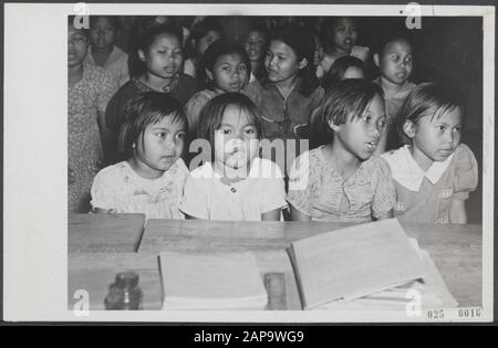 Caption: Medical aid to the Indonesian population in Batavia. A school has been arranged for the children; a few months ago these children were still lying along the roads in Batavia. The monter faces at the singing angles now speak for themselves Date: undated Location: Batavia, Indonesia, Indonesia, Jakarta, Dutch-Indies Keywords: children, music, education, schools, singing Stock Photo