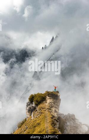 Mountaineer stands on a ridge, behind mountain peaks and pointed rocks, dramatic clouds, Cimon di Croda Liscia and Cadini Group, Auronzo di Cadore Stock Photo