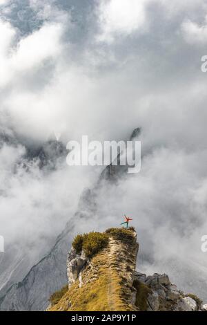 Mountaineer stands on a ridge, behind mountain peaks and pointed rocks, dramatic clouds, Cimon di Croda Liscia and Cadini Group, Auronzo di Cadore Stock Photo