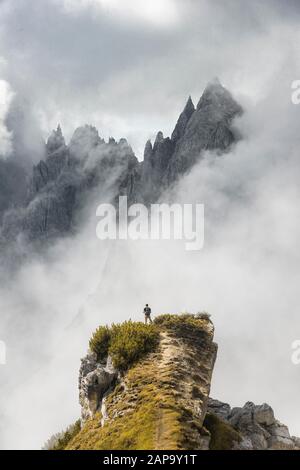 Mountaineer stands on a ridge, behind mountain peaks and pointed rocks, dramatic clouds, Cimon di Croda Liscia and Cadini Group, Auronzo di Cadore Stock Photo