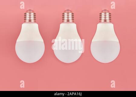 Three light bulbs, copy space. Energy saving minimal idea concept.Pink background. Stock Photo