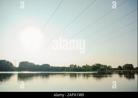 Sunset on the lake and transmission power line. Stock Photo