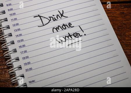 Drink more water, handwriting text on page of office agenda. Copy space. Stock Photo