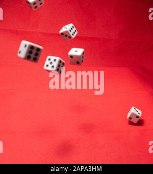 Hand throwing dice, hoping for the best odds. Six dice on red background Stock Photo