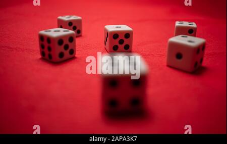 Hand throwing dice, hoping for the best odds. Six dice on red background Stock Photo