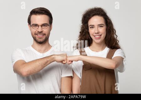 Happy young man in eyewear bumping fists with smiling girl. Stock Photo