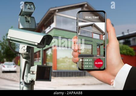 Hand with phone. On the screen interface of remote control surveillance camera Stock Photo