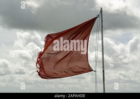 Slightly tatty red flag flying over Salisbury Plain in Wiltshire warning of army activity in the military controlled area. Stock Photo