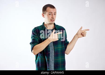 Man points his fingers to the left, makes gestures with his hands and smiles, advertising isolate Stock Photo