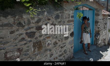 Asian Woman in sunglasses and hat standing in front of traditional Greek house in village of Eressos on islands of Lesvos Stock Photo