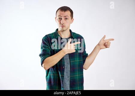 Man points his fingers to the left, makes gestures with his hands and smiles, advertising isolate Stock Photo
