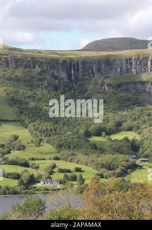 White lakeside house on the shores of Glencar Lake beneath limestone cliffs and waterfall at Glencar beside the Dartry Mountains in Connacht, Ireland. Stock Photo
