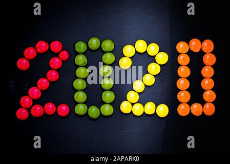 playing with colorful candy coated chocolate buttons on a black background Stock Photo