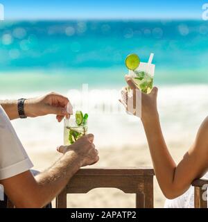 Two cocktail glasses in the hands on sea background. Summer vacation concept. Cool mojito on the beach. Rest on vacation at the belt. Instagram square Stock Photo