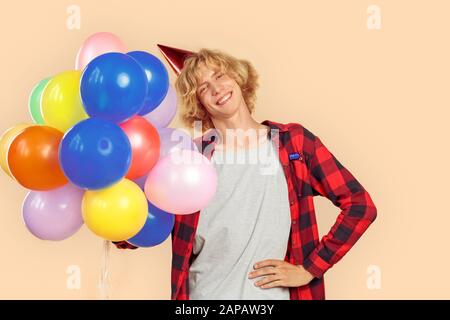 Young man holding helium balloons in hands Stock Photo