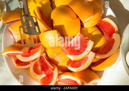 Breakfast concept in the hotel, restaurant, freshly cut slices of juicy grapefruit, a large plate of tropical fruits, sunlight. Stock Photo