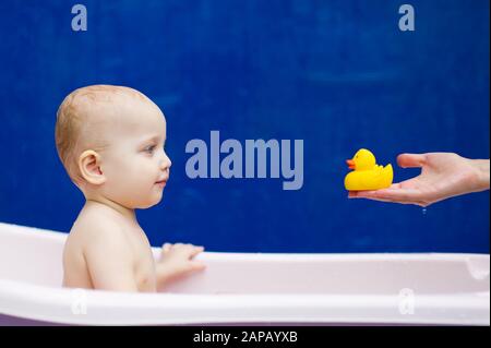 little girl looks at a toy duck in her mother s hand and smiles