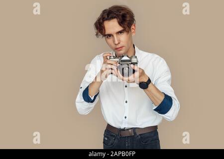 Freestyle. Stylish photographer standing isolated on gray taking photo on camera concentrated Stock Photo