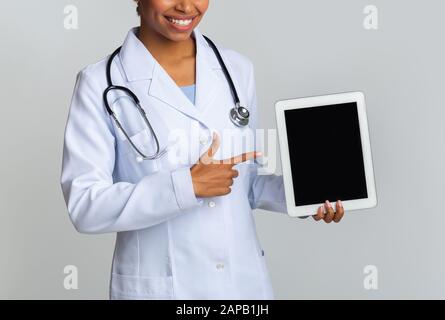 Unrecognizable Black Doctor Pointing At Digital Tablet With Black Screen Stock Photo