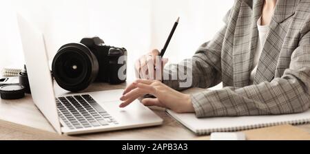 Female journalist working with laptop and camera Stock Photo