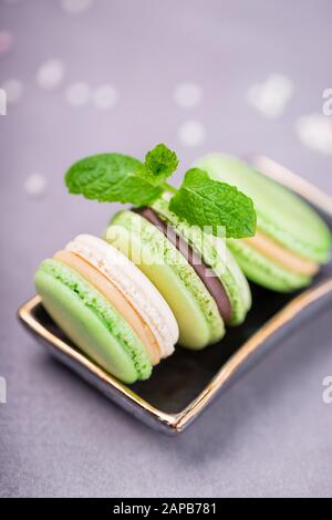 Homemade french macaroons or macarons. Mint cookies with chocolate and vanilla cream on a pale pink background, copy space Stock Photo