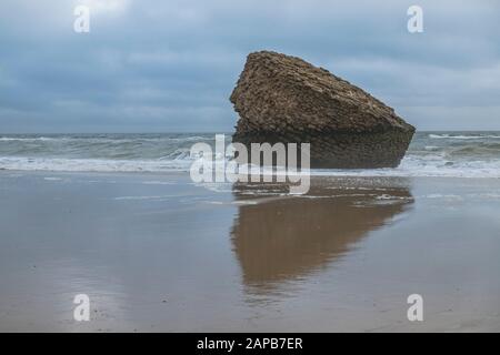 The rock, part of an ancient upside down tower (Torre de la Higuera ) at the beach in Matalascañas, Huelva, Spain. Stock Photo