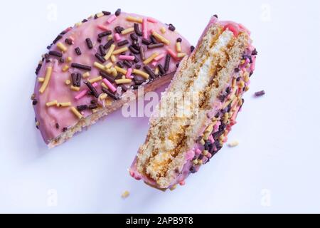 Aldiva Unicorn Wheels strawberry flavour coated marshmallow centered sandwich biscuit with rainbow granules cut to show inside set on white background Stock Photo