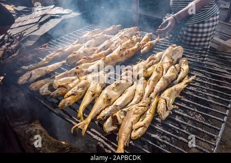 Smoking fish on a grill using charcoal in the port of Banjul in The Gambia Stock Photo