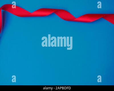 Satin red ribbon on trendy classic blue background. Ready for your design. Can be used for greeting card, holidays, gifts Stock Photo