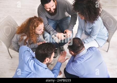 Diverse young people sitting in circle discussing working plan, top view Stock Photo