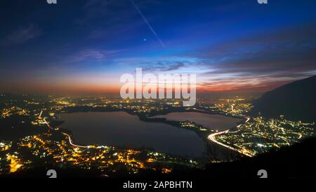 Sunset panorama from Monte Barro above Lake Annone surrounded by colorful lights of cities and streets. Stock Photo