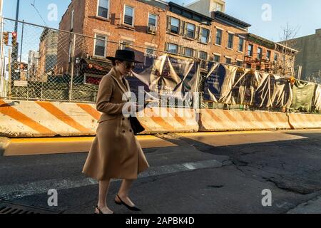 A woman crosses Driggs Avenue in trendy hipster Williamsburg, Brooklyn in New York passing construction of the renovated Bedford Avenue Station on the L line, seen on Sunday, January 12, 2020. (© Richard B. Levine) Stock Photo