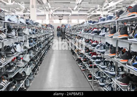 Men's sports sneakers stand on racks in a clothing and shoe store. Stock Photo
