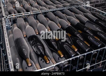 Ancient wine bottles resting, aging, dusting in underground cellar in rows. Concept winery vault with rare wines, exclusive collection. Stacks of wine Stock Photo