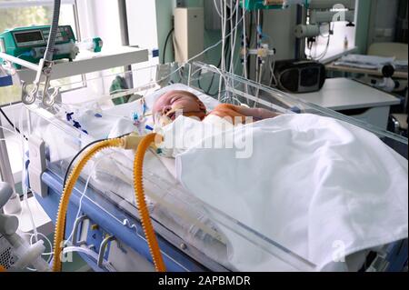 At the intensive care unit. Baby laying on a hospital bed and attached to a reviving apparatus. Children’s Cardiac Center. May 18,2018. Kiev,Ukraine Stock Photo