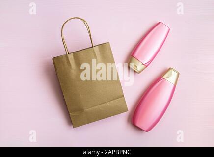 Blank brown paper bag, empty cosmetic bottles on a pink background for print design and mock up. Flat lay. Stock Photo