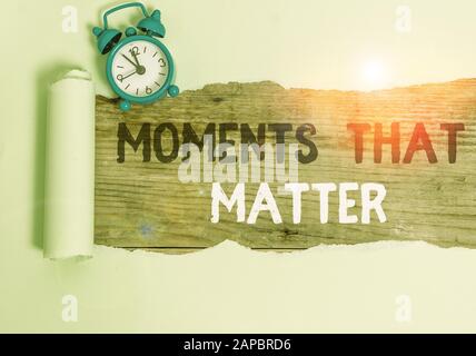 Conceptual hand writing showing Moments That Matter. Concept meaning Meaningful positive happy memorable important times Alarm clock and torn cardboar Stock Photo
