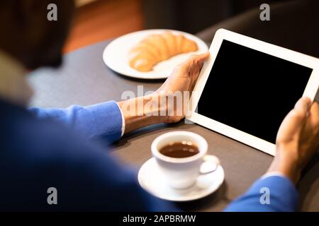 Black man with tablet reading news in cafe shop Stock Photo