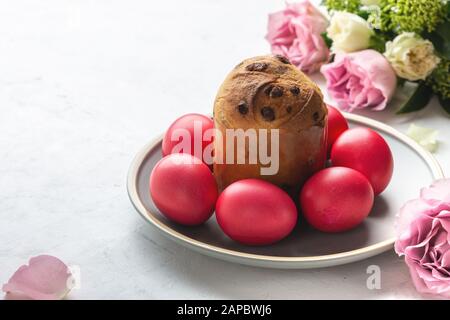 Easter cake, natural dyed red Easter eggs and flowers on holiday festive table Stock Photo
